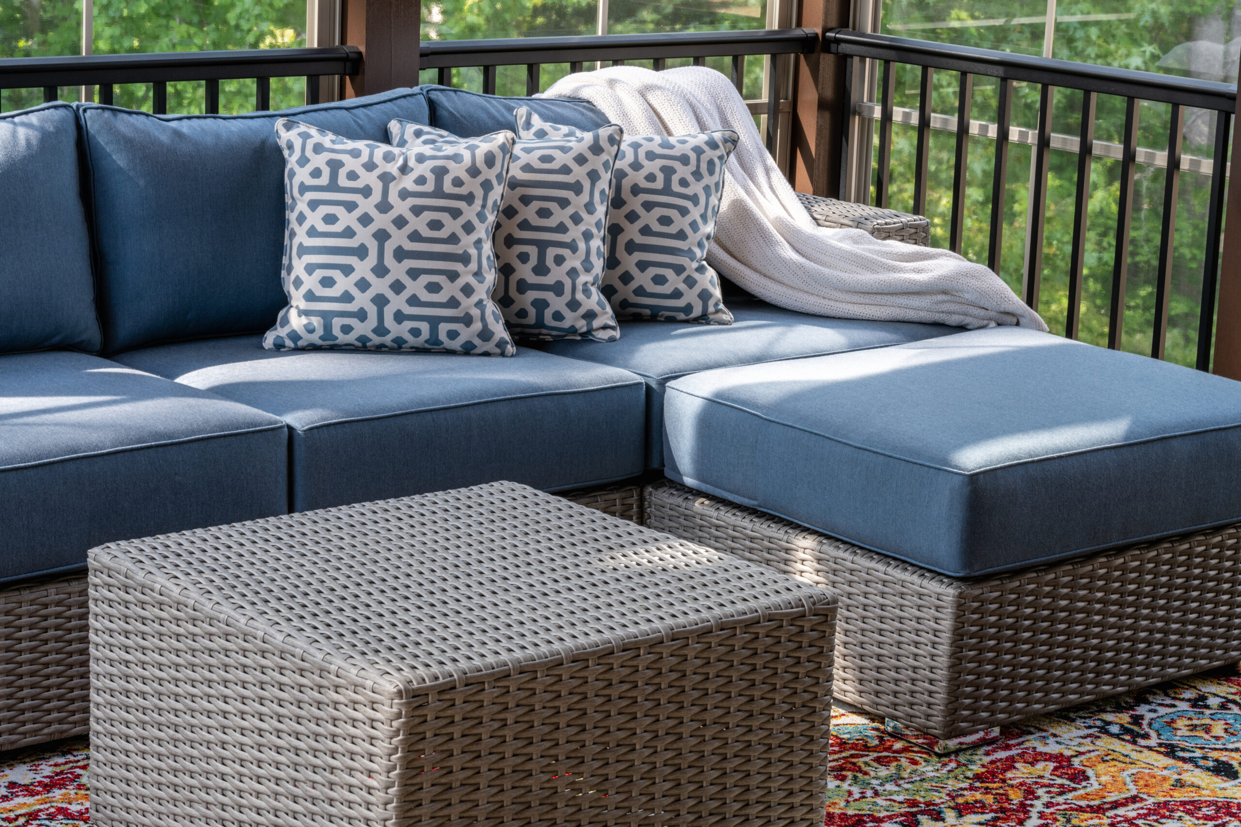 Unique Crafts Outdoor Furniture - Close up of patio furniture in modern screened porch, summertime woods in the background.